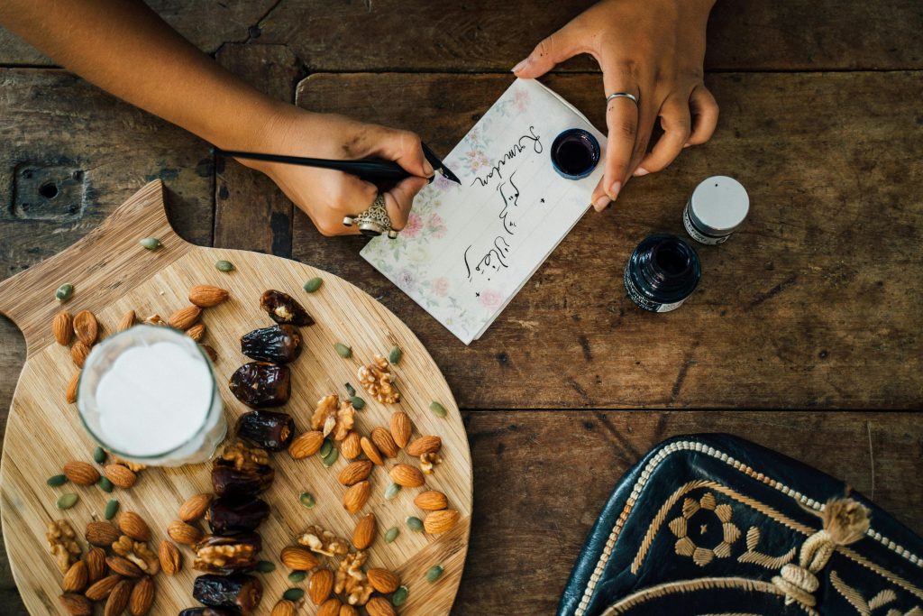 Top view of a table setting for iftar with dates, almonds, and calligraphy writing, embodying Ramadan traditions.